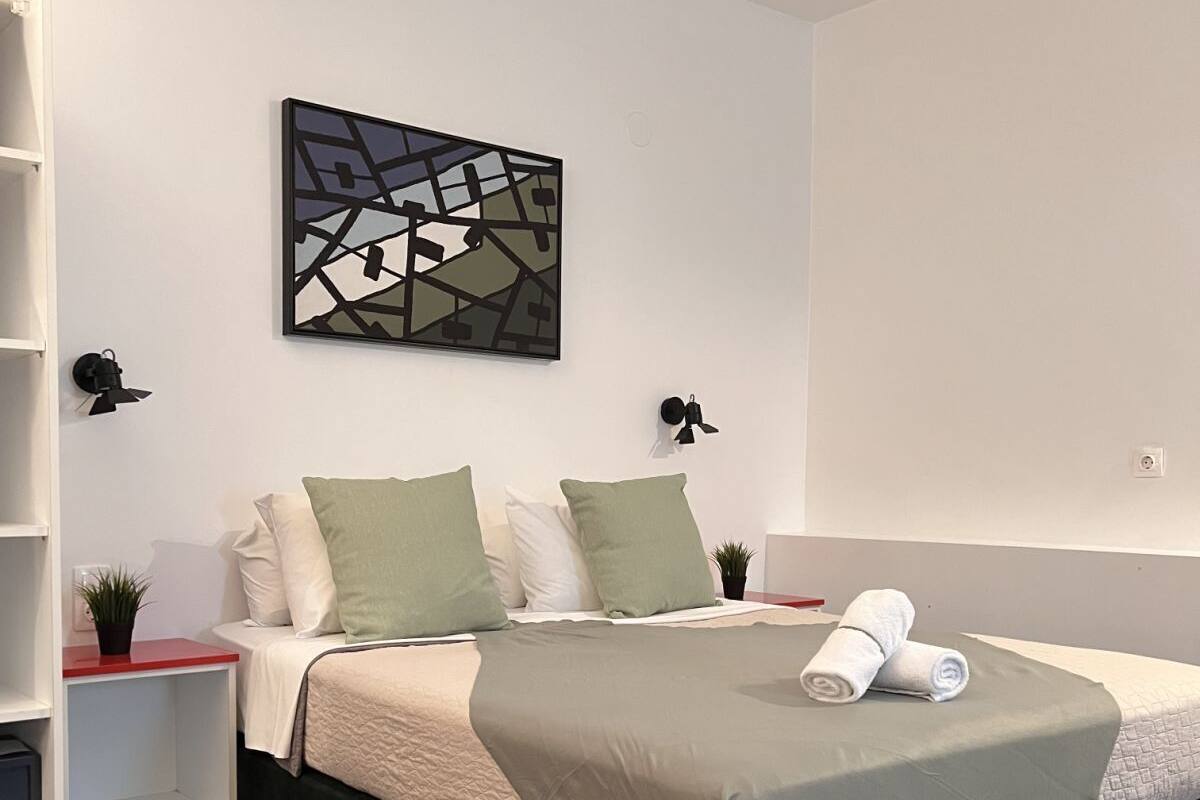 Un dormitorio moderno con una cama, una obra de arte con un mapa y una planta pequeña en una mesita de noche.