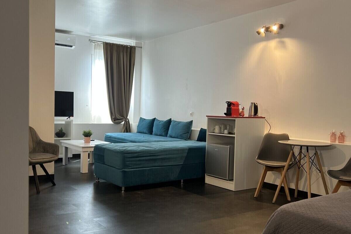 Una habitación de hotel moderna con una cama grande, un escritorio, una kitchenette pequeña y una zona de estar.