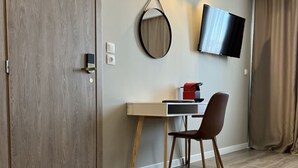 Una habitación moderna con suelo de madera, un escritorio con silla, un televisor de pantalla plana y una puerta corredera.