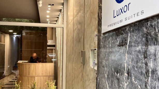 Una zona de recepción con pared de mármol y un letrero que indica 'Luxor Premium Suites'.