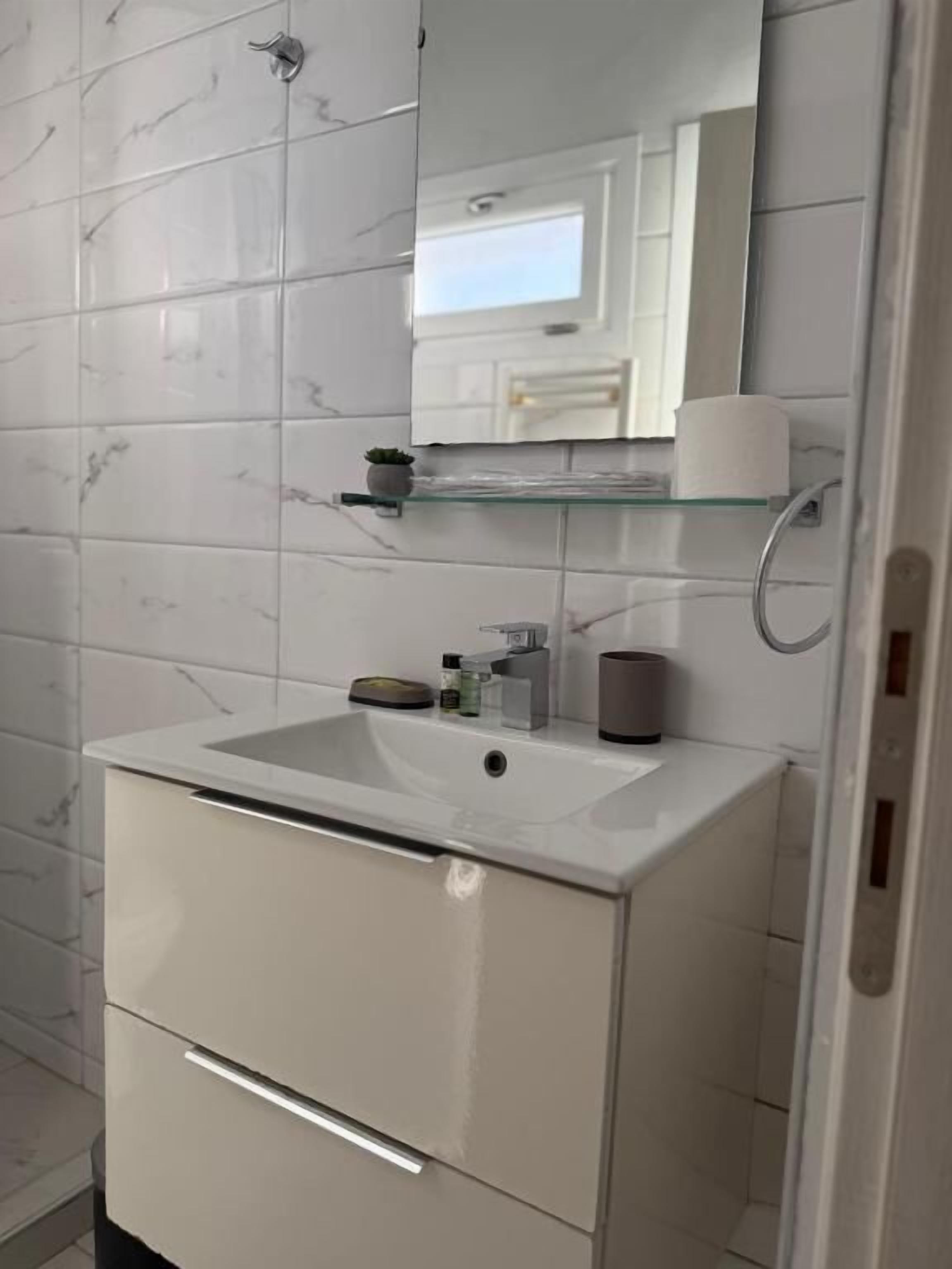 Ein Badezimmer mit einem weißen Waschbecken, Spiegel und Ablagekorpus.