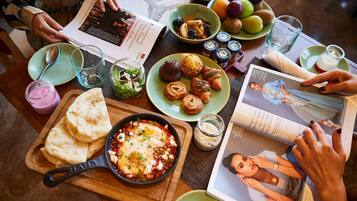 A table with various food items, a magazine, and a book.