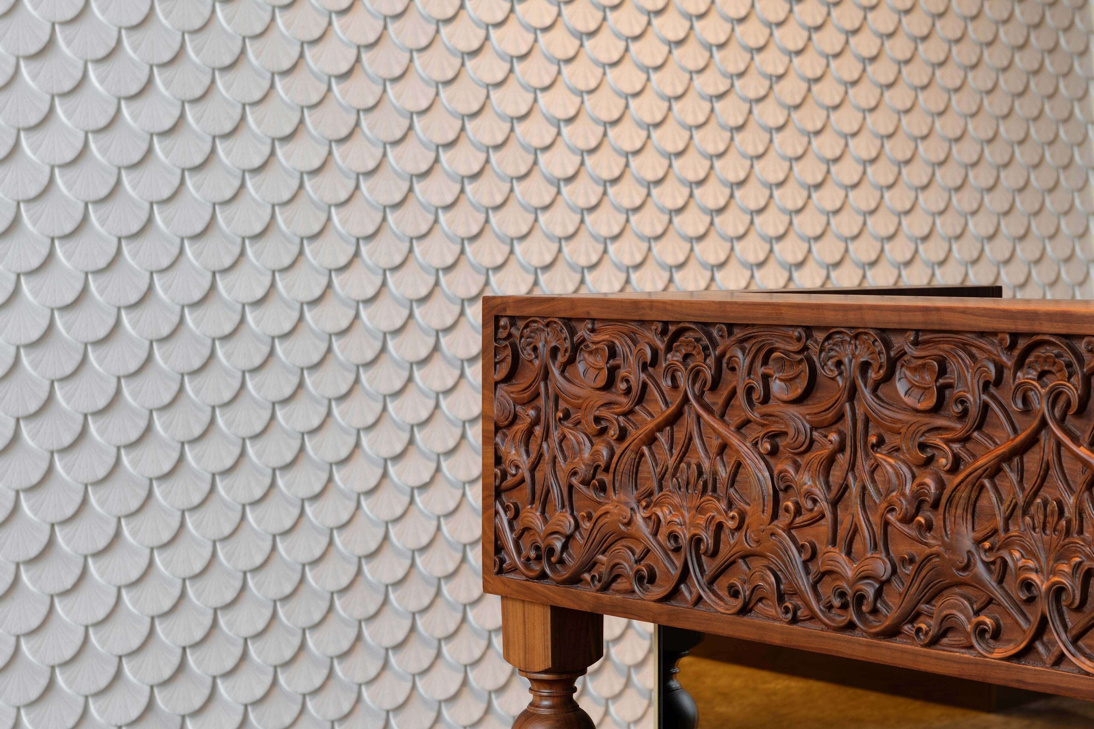 Un banco de madera con detalles tallados sobre un muro con textura.