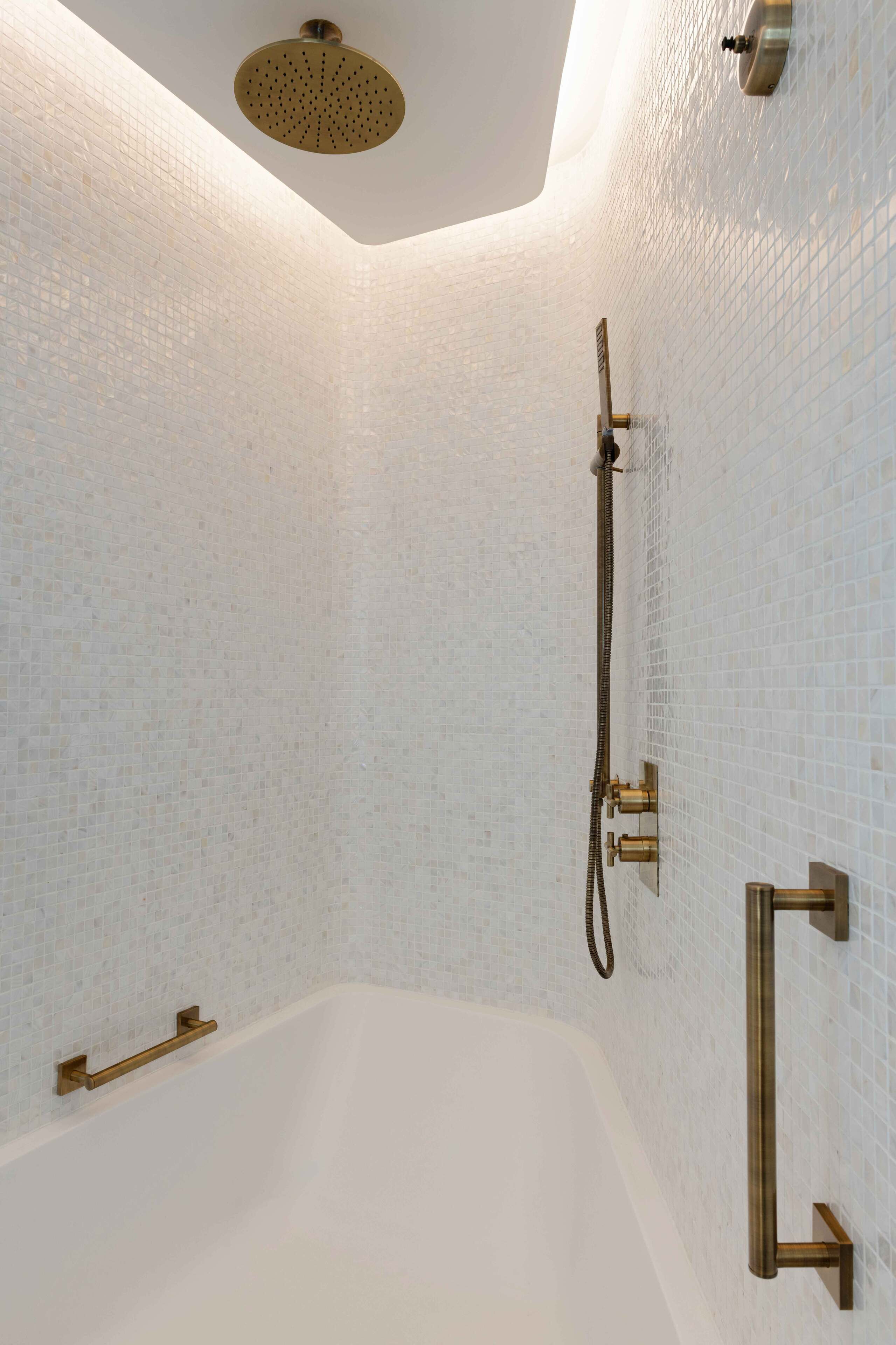 Un baño moderno con una bañera independiente, un cabezal de ducha de mano y un grifo empotrado.