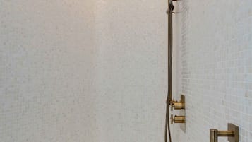 Un baño moderno con una bañera independiente, un cabezal de ducha de mano y un grifo empotrado.
