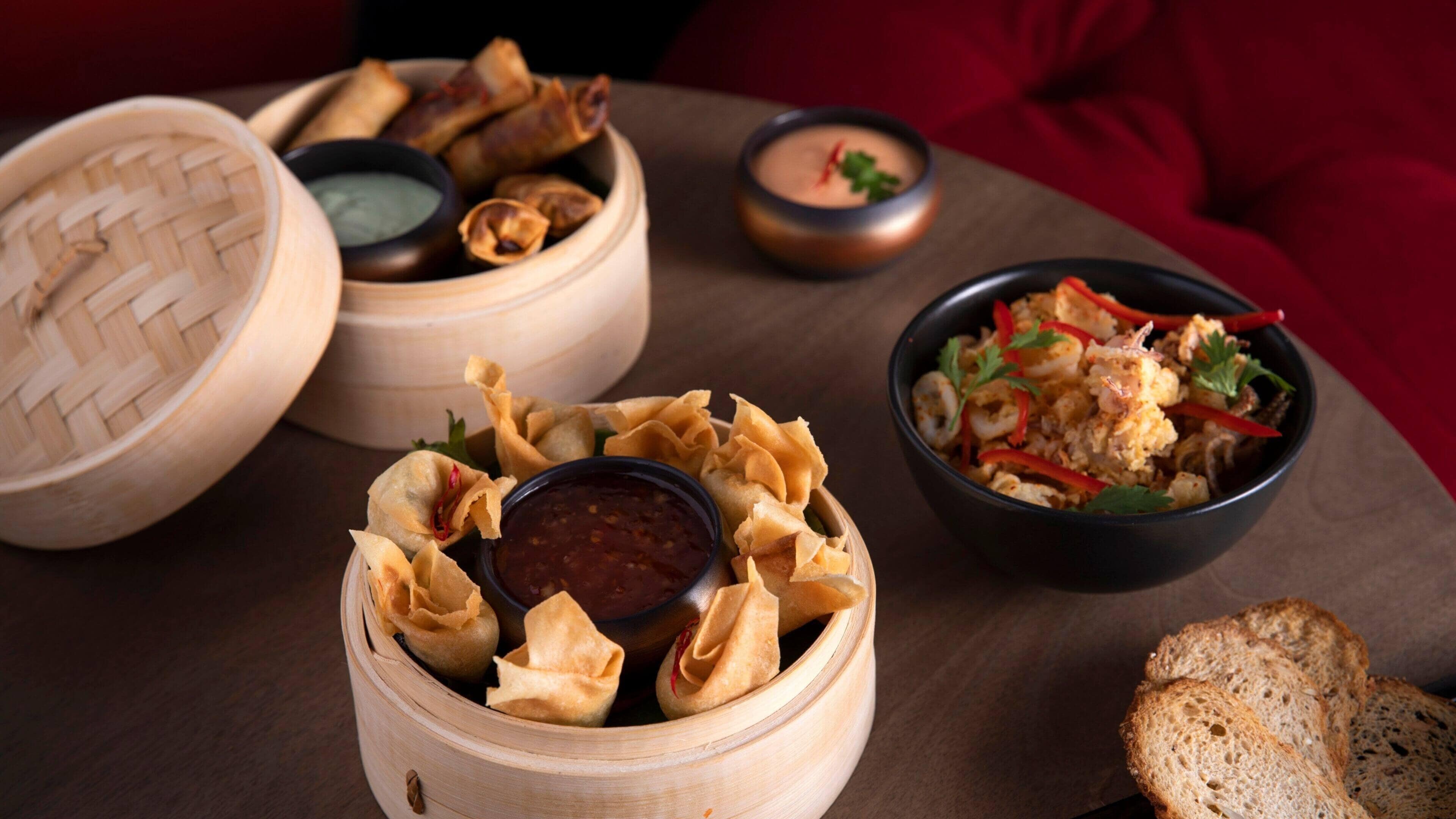 A table with food items including dumplings, a bowl of rice with shrimp, and bread.