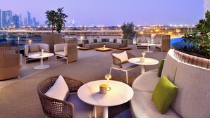 Un salon sur le toit, doté d’espaces salon, de tables et offrant une vue sur le panorama urbain.