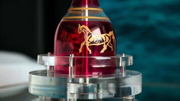 A red vase with a gold horse design on a clear stand.
