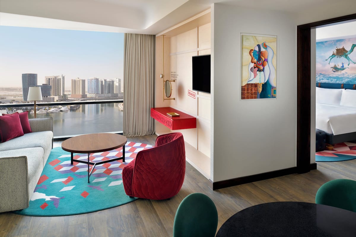 Ein modernes Hotelzimmer mit Blick auf die Stadt, einem roten Sofa, einem runden Couchtisch und einem Gemälde an der Wand.
