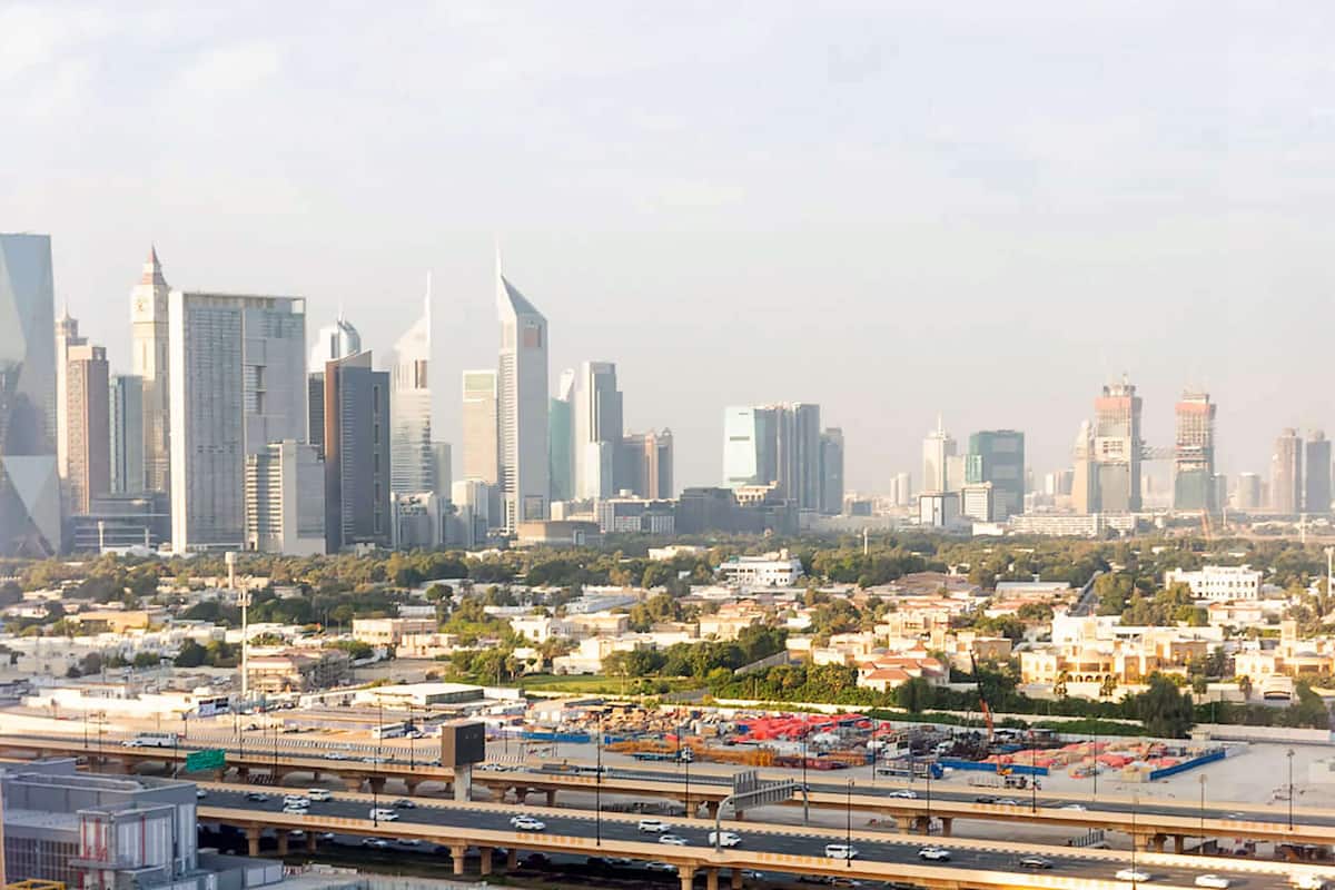 A cityscape with modern high-rise buildings, a busy highway, and a construction site.