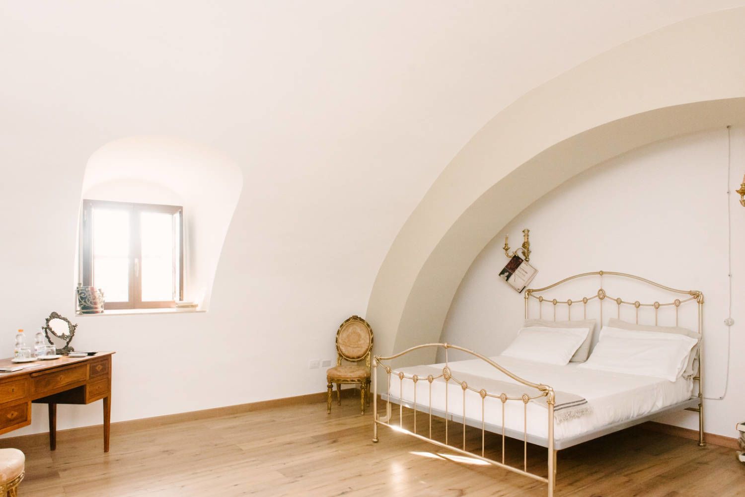 A bedroom with a bed, a desk, a chair, and a window.