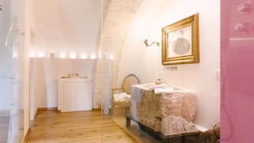Sink and chair in a cozy room with a stone wall and wooden floor.