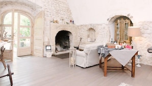 A rustic stone interior with a fireplace, a white sofa, and a table with various items. - B&B Barone Gambadoro (Monte Sant'Angelo)