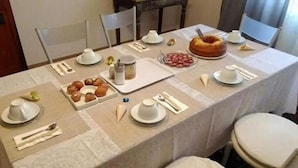 Una mesa de comedor dispuesta con platos, cubiertos y un pastel, rodeada de sillas.