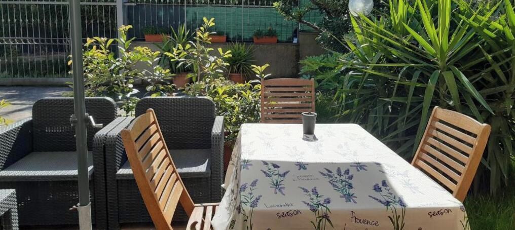 Uma área de estar ao ar livre com móveis de vime e uma mesa coberta por um tecido de mesa floral.