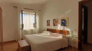 Un dormitorio con cama, mesita de noche, ventana con cortinas y decoración en la pared.
