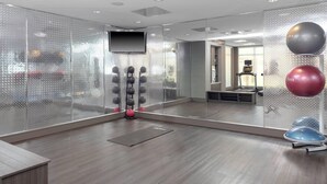 Een moderne sportschool met een spiegelwand, trainingsapparatuur en een loopband.