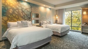 A hotel room with two beds, a large window with a view of trees, and a wall mural. - Courtyard by Marriott West Springfield (West Springfield)