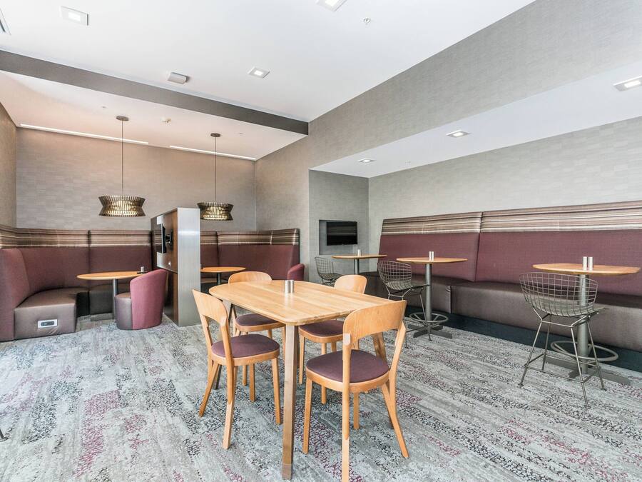 A modern restaurant with booth seating, wooden tables, and a patterned carpet.