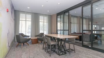 Una sala de reuniones moderna con una gran mesa, sillas cómodas y un panel de vidrio.