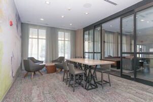 Una sala de reuniones moderna con una gran mesa, sillas cómodas y un panel de vidrio.