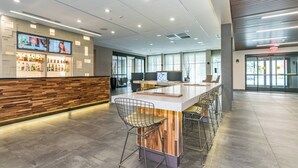 A modern bar area with a long counter, multiple bar stools, and a wooden accent wall. - Courtyard by Marriott West Springfield (West Springfield)
