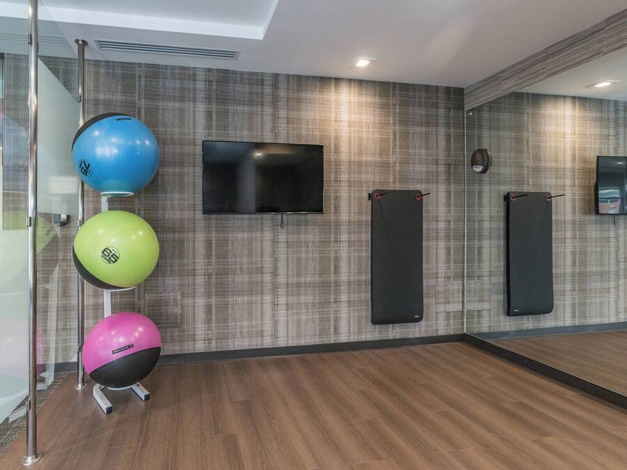 Una palestra con palle da ginnastica, una TV e attrezzature fissate al muro.