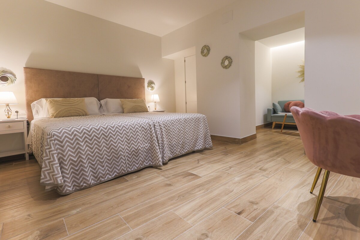 A bedroom with a bed, bedside tables, a nightstand, a chair, and a door.