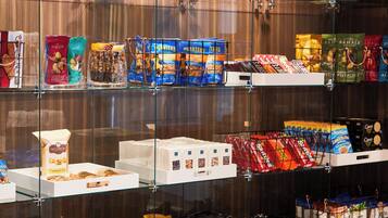 Ett urval av snacks och matvaror som presenteras på hyllor av glas.