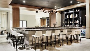 A modern kitchen with a central island, bar stools, and a wine rack. - AC Hotel by Marriott Huntsville Downtown (Huntsville)