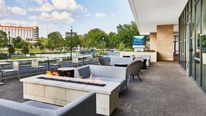An outdoor patio area with seating, a fire feature, and a view of a hotel sign. - AC Hotel by Marriott Huntsville Downtown (Huntsville)