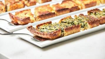 A white rectangular plate with several pieces of quiche on a white surface.