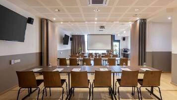 A conference room with a long table, multiple chairs, a projector screen, and a large window.