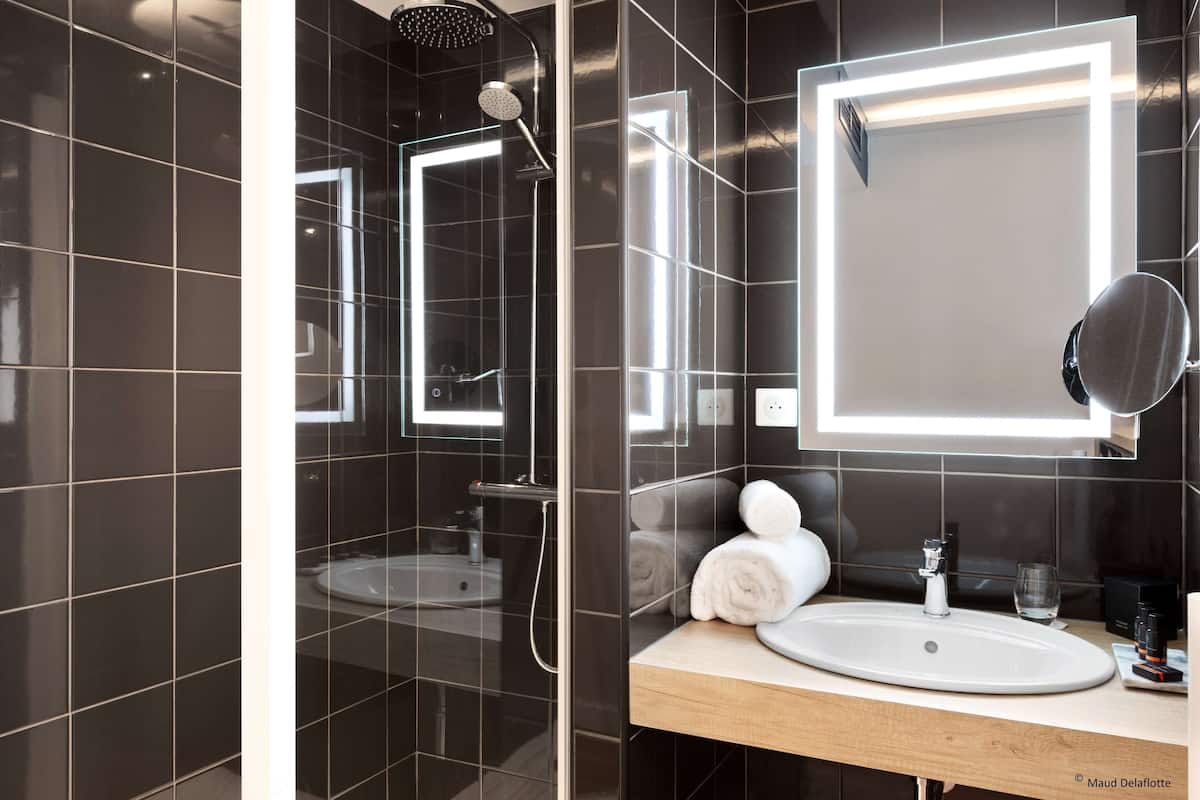 Une salle de bain moderne avec une douche à parois de verre, un meuble-lavabo et un grand miroir.