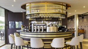 A bar area with a circular design, bar stools, and a chandelier.