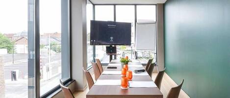 A modern conference room with a large table, chairs, and a flat-screen TV.