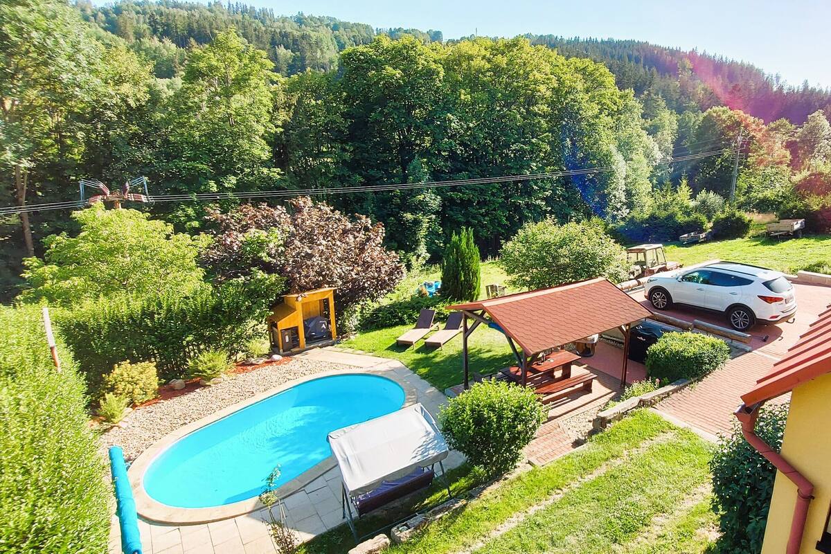 A residential area with a swimming pool, a car parked in the driveway, and a house with a red roof.