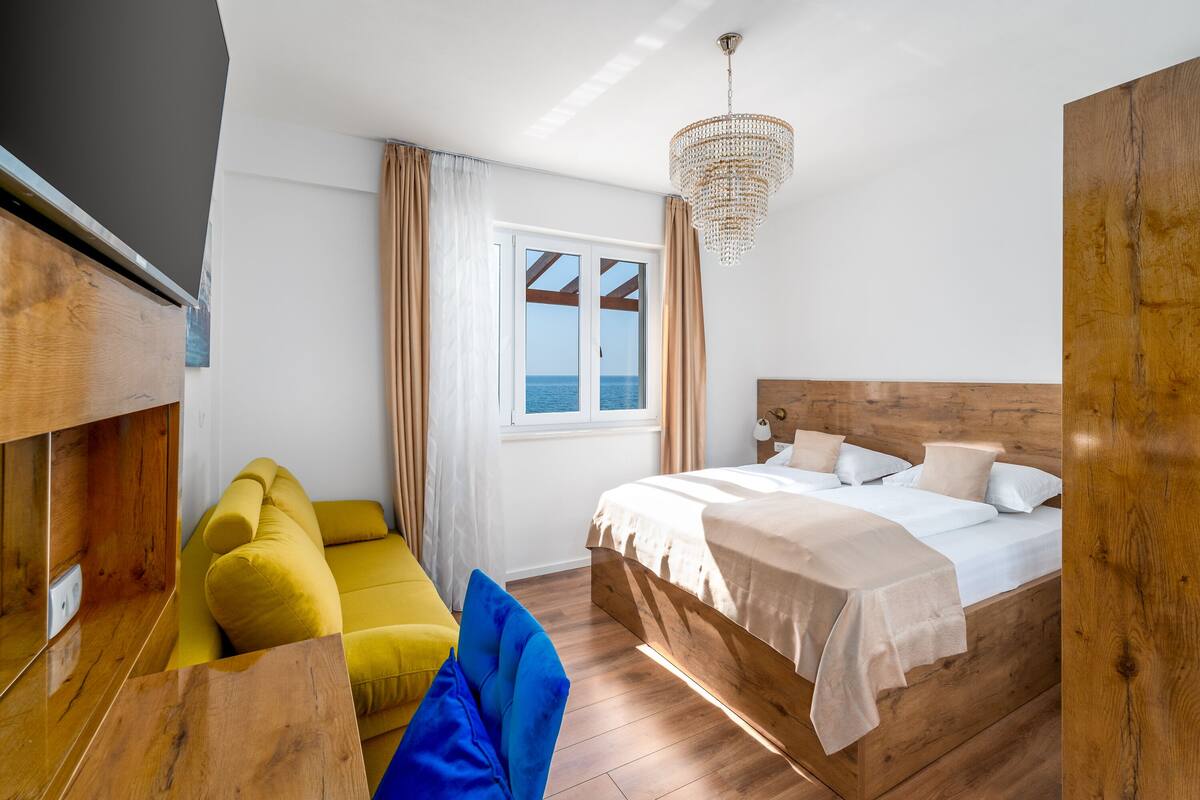 Une chambre à coucher avec un lit en bois, un canapé, une table et une vue sur la mer par la fenêtre.