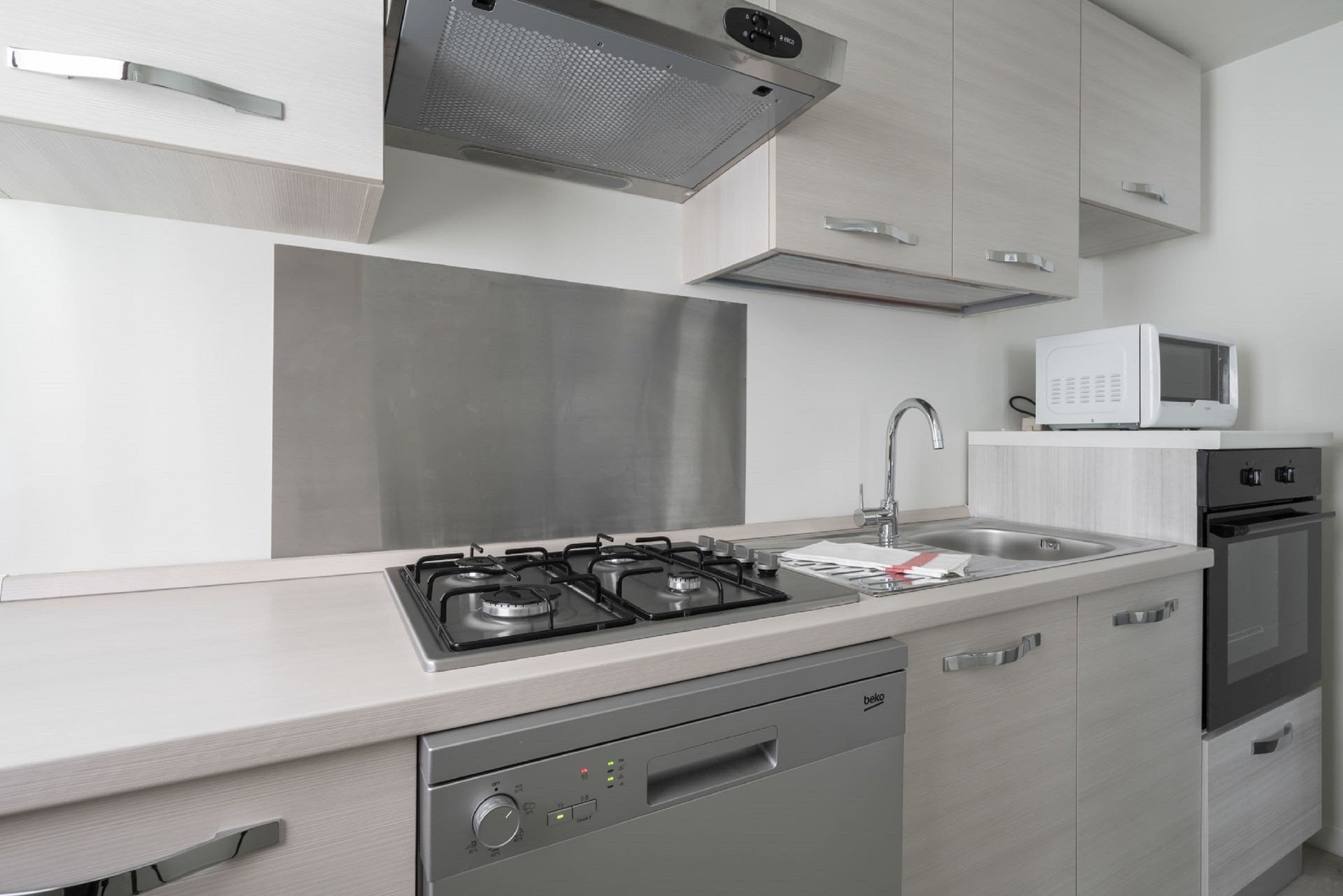Cozinha moderna com eletrodomésticos de aço inoxidável, micro-ondas e lava-louças.