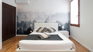 A bedroom with a bed, a nightstand, a wall-mounted air conditioner, and a window. - Apartments in San Marco with Canal View by Wonderful Italy (Venice)