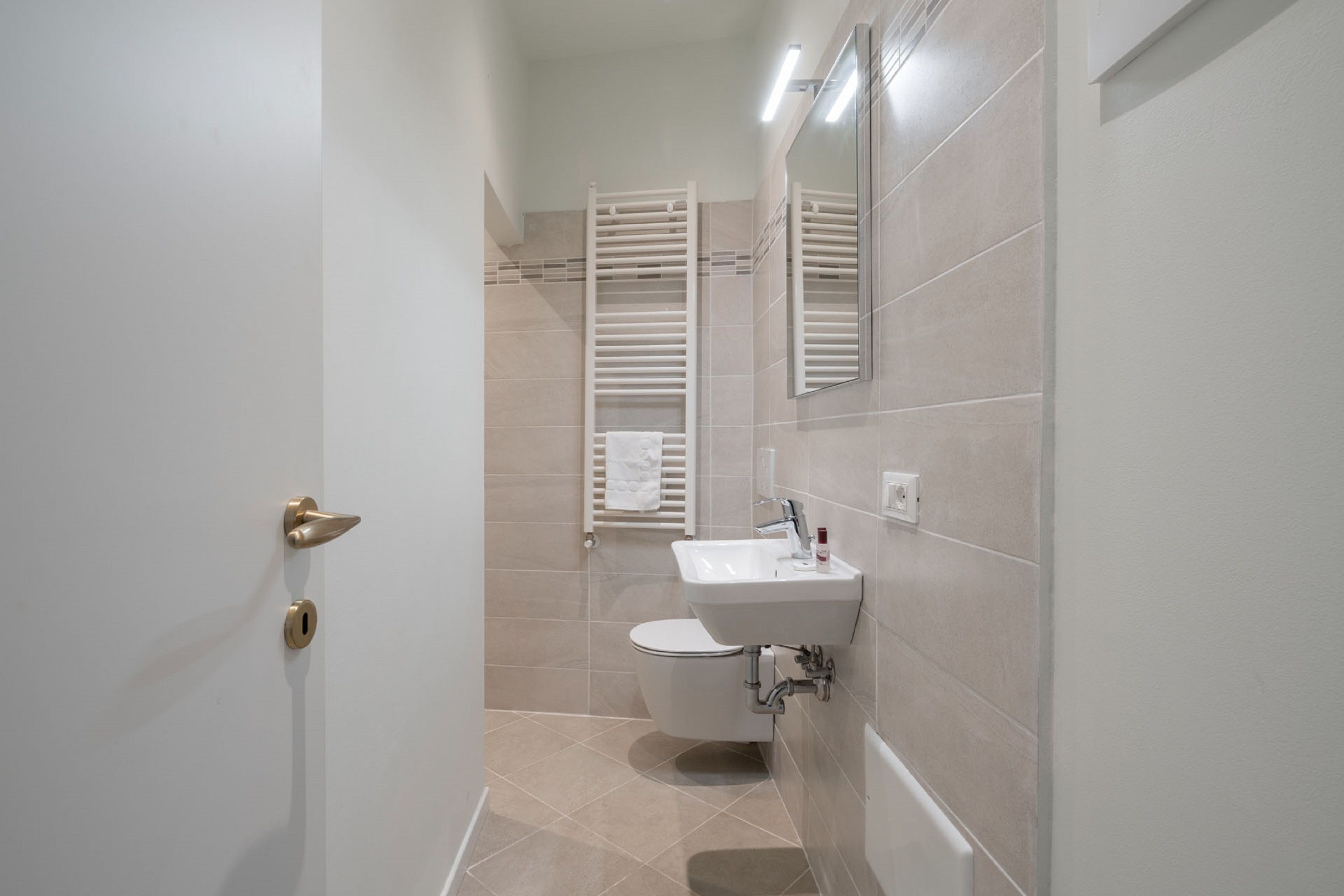A bathroom with a toilet, sink, and towel rack.