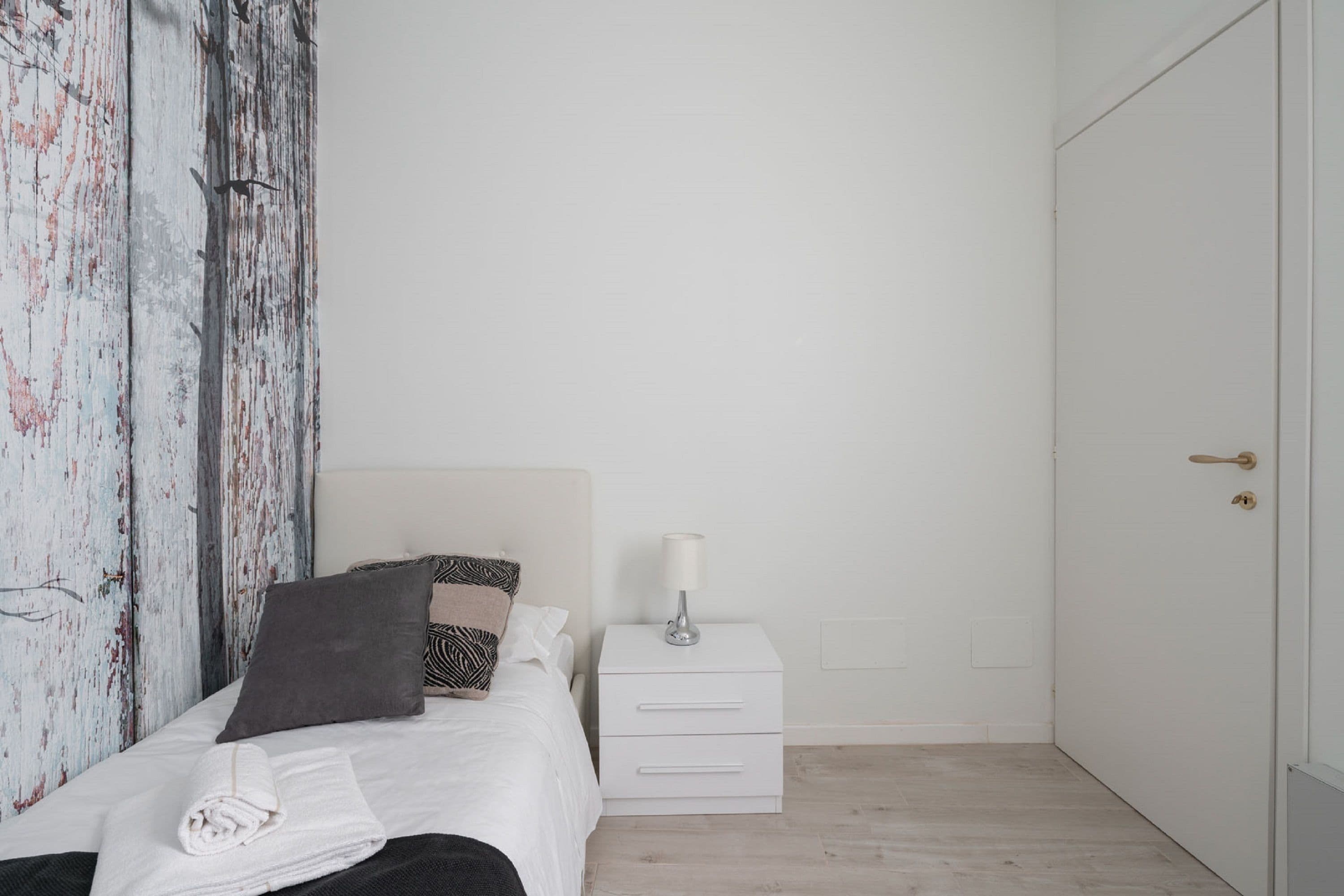 Quarto com cama, mesa de cabeceira e guarda-roupa.