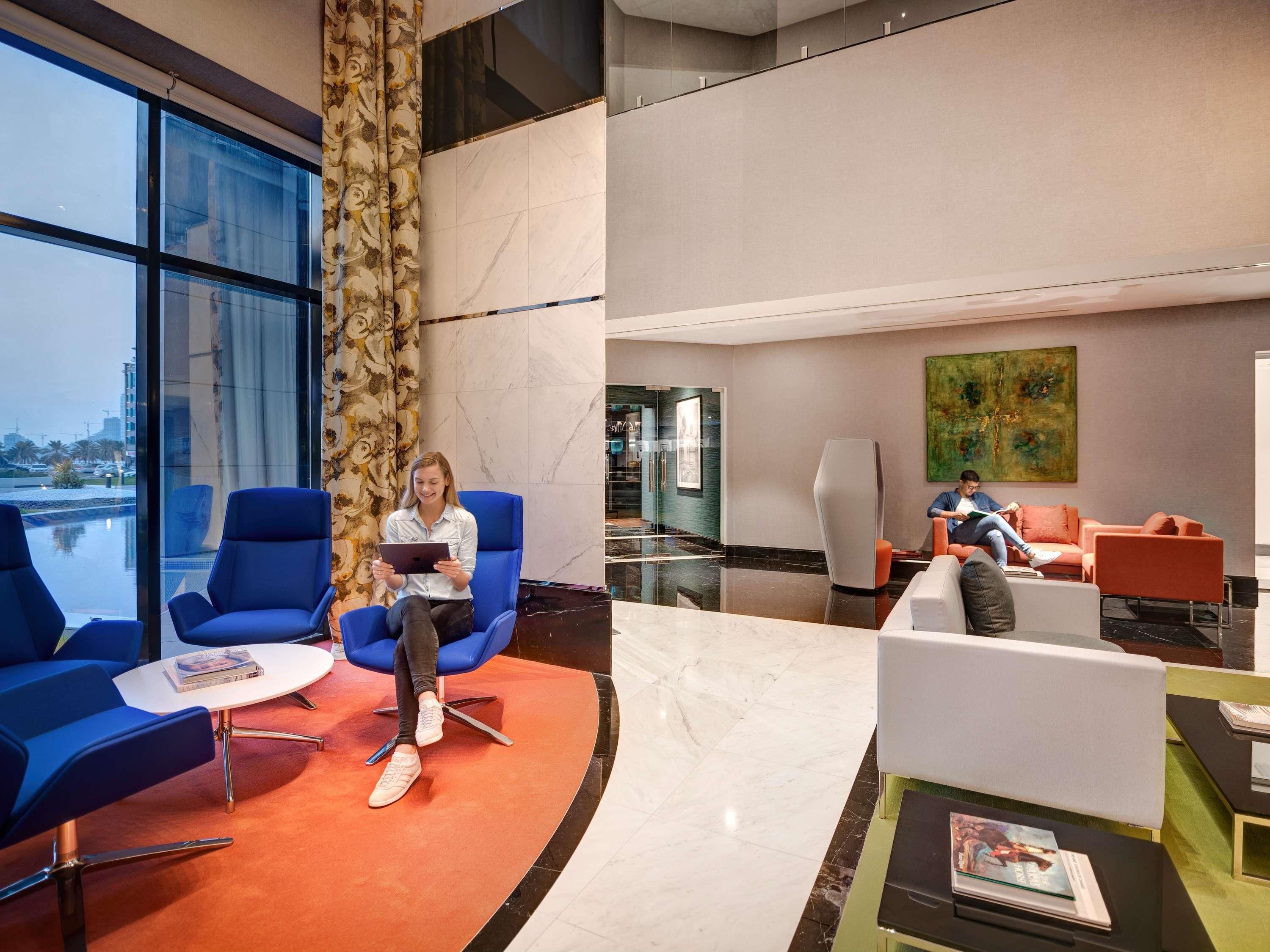 A modern lobby with blue seating, a glass wall, and a large painting.