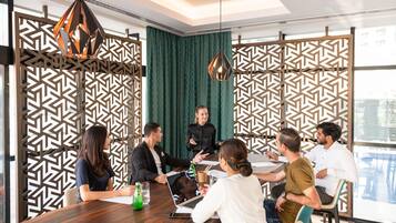 A modern meeting room with a wooden table, patterned partitions, and pendant lighting.