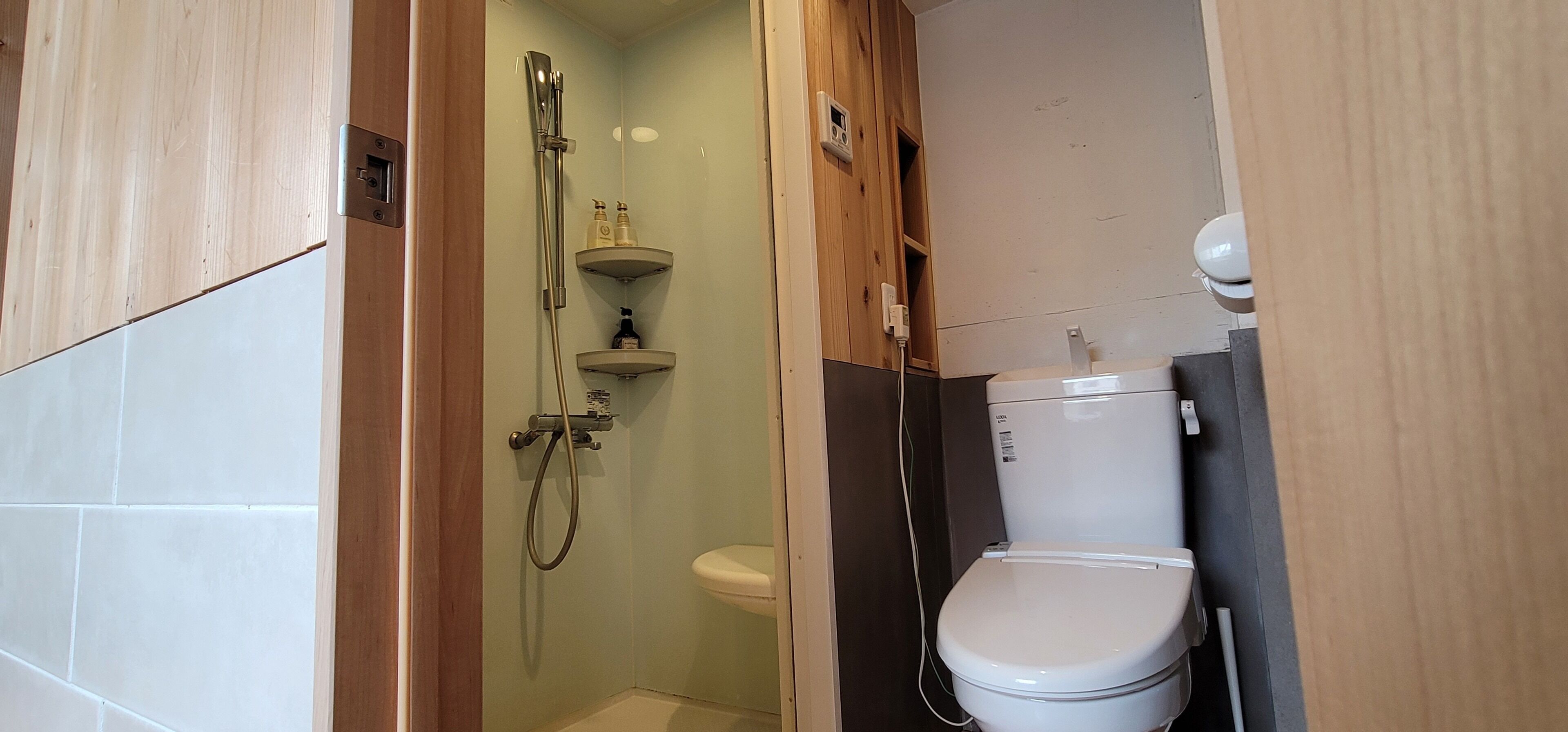 A bathroom with a shower, toilet, and a shelf with toiletries.