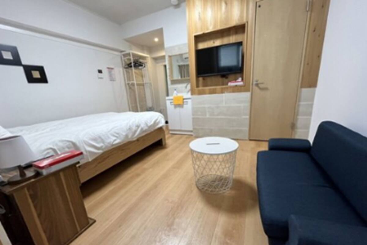 Una habitación compacta con una cama, un escritorio pequeño, una mesa de centro redonda y un sofá.