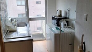 Une petite cuisine équipée d’un four à micro-ondes, d’une bouilloire et d’un évier.