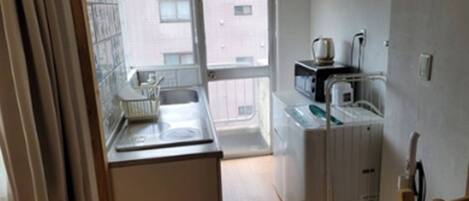Una pequeña cocina equipada con microondas, hervidor y lavabo.