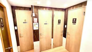 A hotel bathroom with four wooden doors, each marked with a sign indicating a shower and a toilet.
