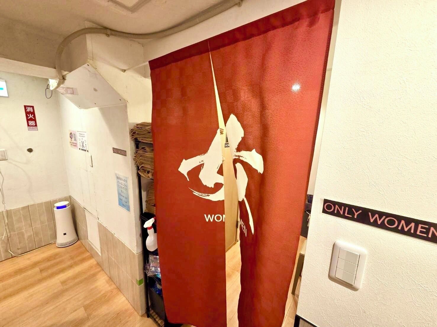 Baño de mujeres con una cortina roja y un letrero que indica que es exclusivo para mujeres.